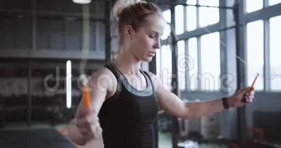 身材矮小的年轻运动金发女人用跳绳锻炼身体在大的大气健身房里累得满头大汗视频的预览图