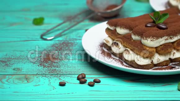 两份经典的提拉米苏甜点在彩色蓝色木制背景的陶瓷盘子上视频的预览图