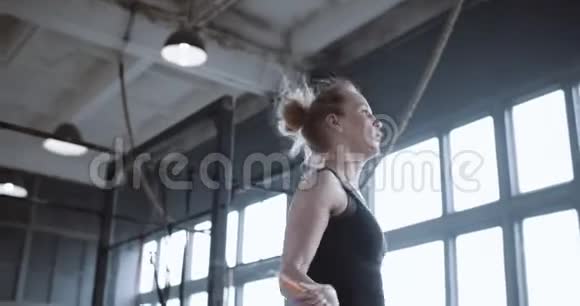 低角度侧视美丽年轻快乐运动金发女人与跳绳在大型健身房慢动作视频的预览图