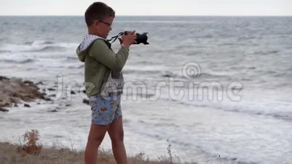 海滩暑假带着相机在海滩上的男孩视频的预览图