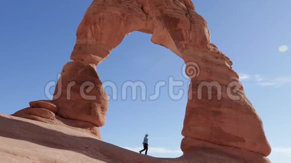 在国家公园橙色岩石的精致拱门上女人举起双手视频的预览图