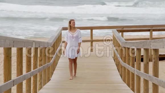 可爱的女孩在海滩上的木墩上散步视频的预览图