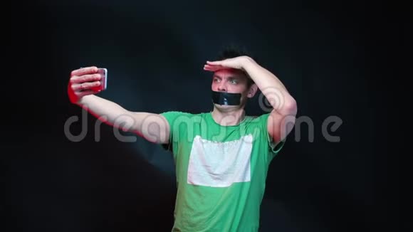 一个穿着绿色衣服嘴巴密封的人在黑色背景上写博客视频的预览图