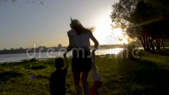 母亲带着男孩和女孩在草地上跳跃视频的预览图