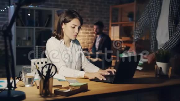 当经理晚上带更多的文件时一个疲惫的女孩在用笔记本电脑工作视频的预览图