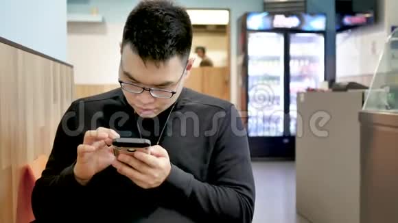 亚洲帅哥在电话里愉快地聊天盖伊在使用智能手机时微笑着视频的预览图