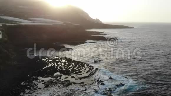 在火山熔岩形成的日落海浪在野生海滩和香蕉树的田野在悬崖下的温室视频的预览图