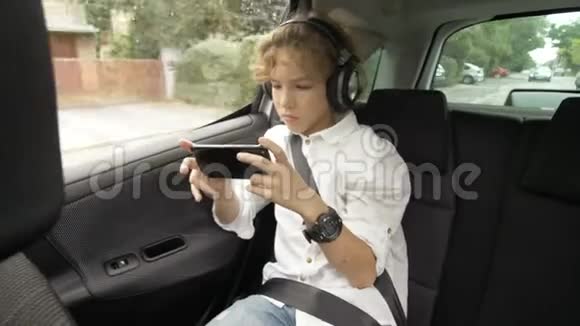 一个带着耳机的男孩开车穿过城市在智能手机上使用社交网络视频的预览图