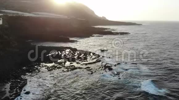 在火山熔岩形成的日落海浪在野生海滩和香蕉树的田野在悬崖下的温室视频的预览图