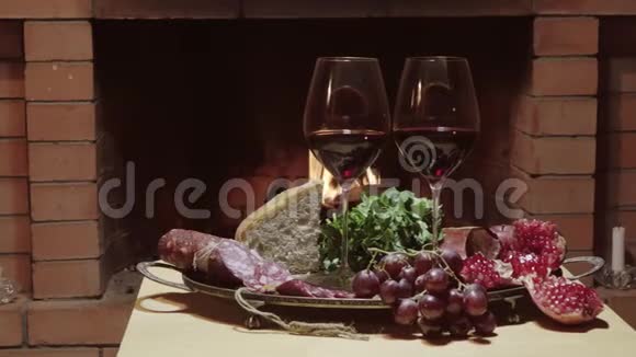 两杯葡萄酒奶酪面包和水果在火灾背景下娃娃射击视频的预览图