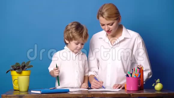 妈妈和孩子一起度过时光家庭幸福观念妈妈教儿子蓝色背景女人和小男孩视频的预览图