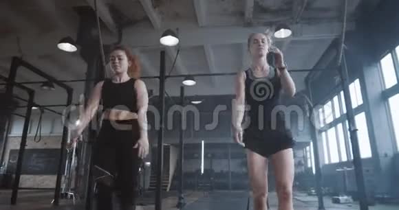 慢动作年轻漂亮的运动金发女郎和职业女教练一起在大气层健身房锻炼视频的预览图