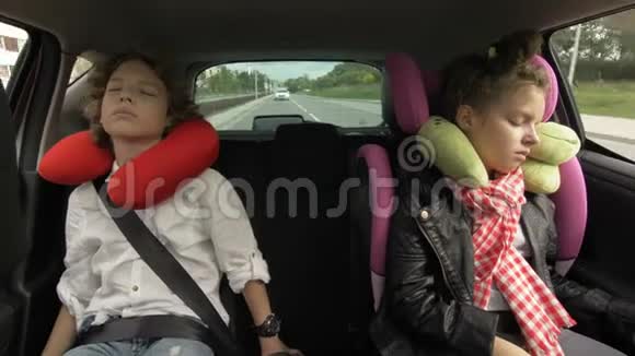 青少年男孩和女孩带着旅行枕头睡在汽车座椅上骑在后座兄妹旅行视频的预览图