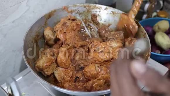 印度厨房用煤气火焰在钢制煎锅中搅拌咖喱肉汁视频的预览图