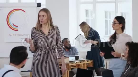 年轻的金发商务女性老板领导积极的团队讨论交谈和手势在现代办公室挂图视频的预览图