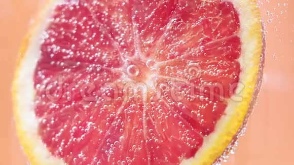成熟的红橙葡萄柚在苏打水中有气泡选择性聚焦多汁的成熟水果在水中近点视频的预览图