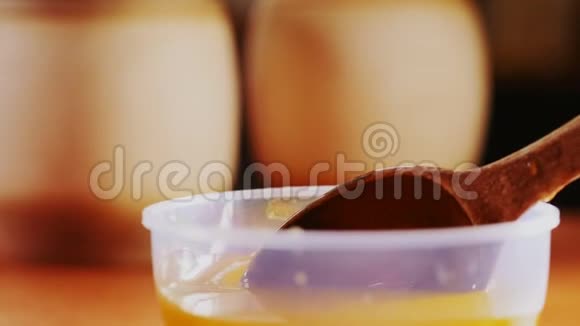 在塑料碗上倒入蜂蜜的粗茶匙近视景视频的预览图