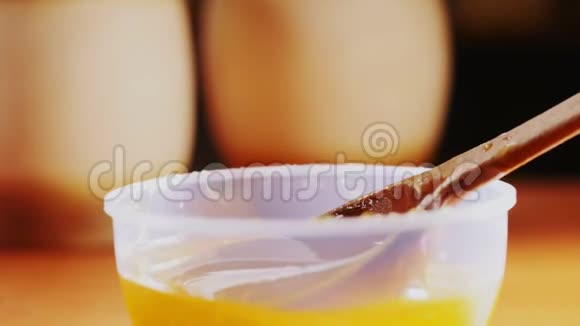 在模糊的背景下在碗上放蜂蜜的木勺视频的预览图