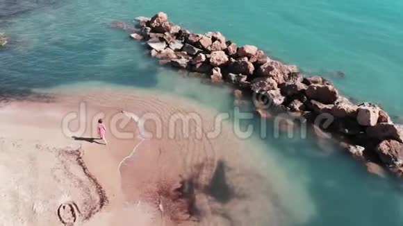 年轻女孩在沙滩上散步海滩上穿红色裙子的漂亮女人用清澈的海水俯瞰美丽的海滩女孩视频的预览图