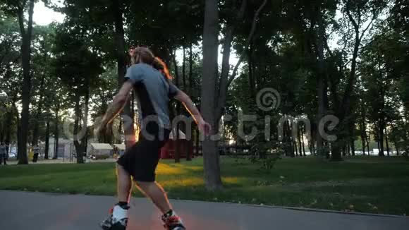 年轻的长发胡须男滑轮手正在一个美好的夜晚在一个城市公园跳舞显示拇指向上自由式视频的预览图
