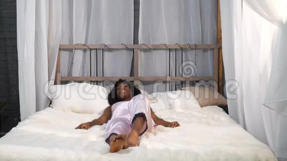 微笑的非裔美国女士醒来后躺在床上视频的预览图