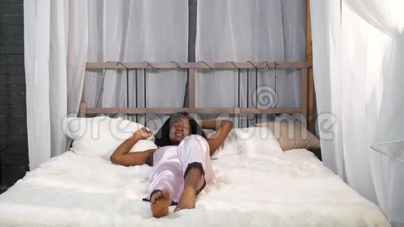 微笑的非裔美国女士醒来后躺在床上视频的预览图