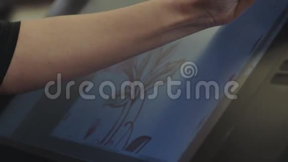 设计师在一个图形平板上画画使用交互式笔显示在图形平板上画画特写视频的预览图