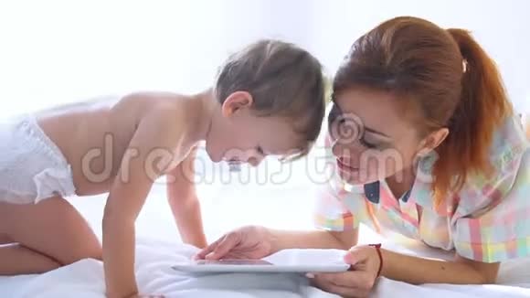 妈妈和儿子在床上看智能手机视频的预览图