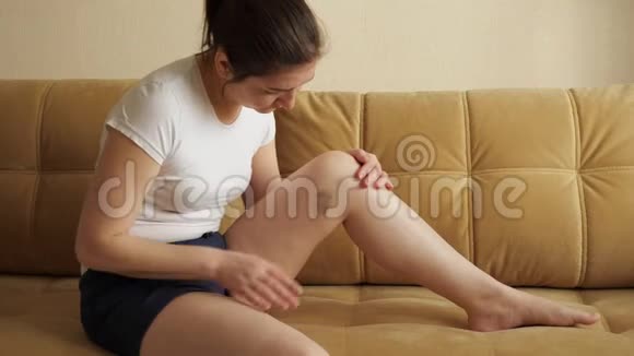 坐在沙发上的女人检查她腿上的伤视频的预览图