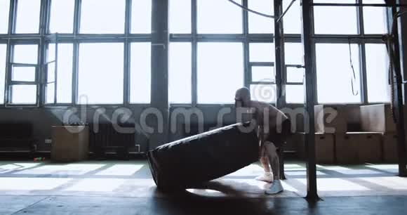 极限锻炼肌肉年轻的赤膊男子与巨大的轮胎在训练在健身房侧视慢动作视频的预览图