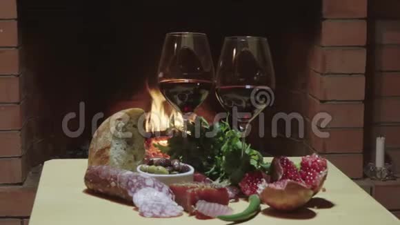 两杯葡萄酒奶酪面包和水果在火灾背景下娃娃射击视频的预览图