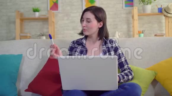 年轻迷人的微笑女人带着怀孕测试坐在沙发上手提电脑视频的预览图