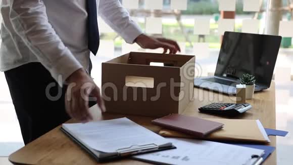 辞职后年轻的男员工站在工作桌旁把他的东西放进纸箱里视频的预览图