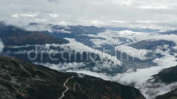 在美丽的群山之上的云层中飞行山区公路视频的预览图