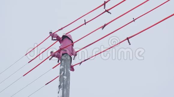 杆顶和带粉红色材料的电缆在灰色的天空上视频的预览图