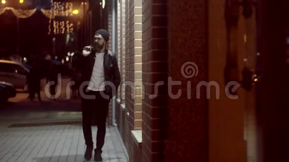 有魅力的家伙晚上在户外接手机孤单一人光明的街道一个英俊的长胡子男人独自走回家视频的预览图