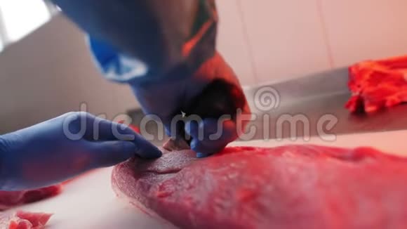 穿着制服的工人在餐桌上用刀切鲜猪肉视频的预览图