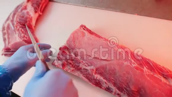 戴着橡胶手套的屠夫在餐桌上切鲜肉视频的预览图