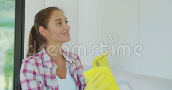 女人一只黄色的橡胶手套用一块布清洁了现代塑料厨房橱柜闪亮的表面这就是视频的预览图