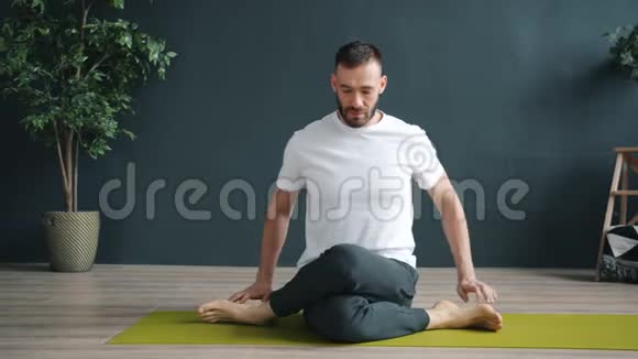 男性成人独自在健康中心的牛脸位置练习瑜伽视频的预览图