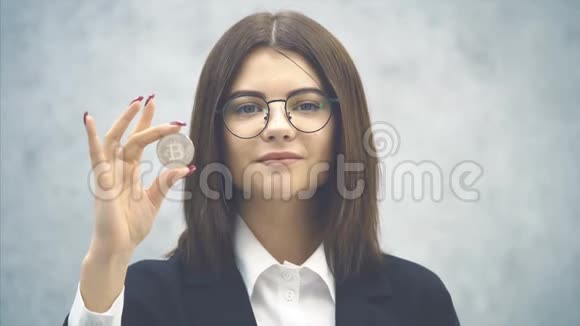 自信的年轻女商人穿着正式的黑色西装手里拿着一枚银币手指指着银币点头表示视频的预览图