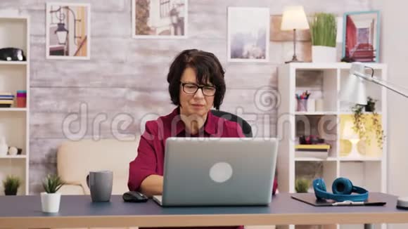 老年妇女在笔记本电脑上浏览时喝咖啡视频的预览图
