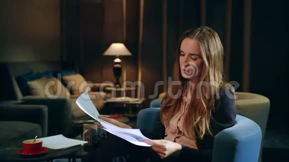 愤怒的商务女性晚上在酒店大堂阅读财务报告视频的预览图