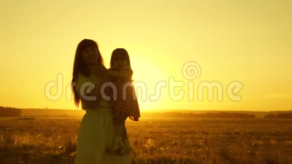 妈妈和小女儿在日落时跳舞母亲正和一个孩子在田里跳舞幸福的概念视频的预览图