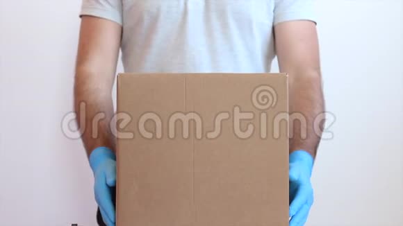 男人打开一个戴着蓝色医疗手套的纸板箱在医用手套里拆箱非接触交货视频的预览图