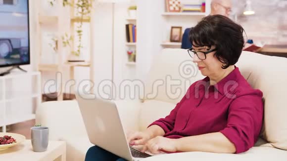 退休妇女在笔记本电脑上打字的侧视图视频的预览图