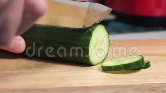 切黄瓜一个人用手在木切割板上用刀切黄瓜沙拉的配料视频的预览图