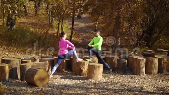 在秋天的森林里几个运动员用木头做腿伸展视频的预览图