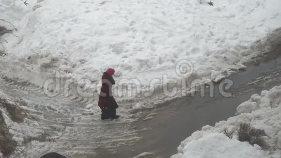 女人穿过水坑和潮湿的雪视频的预览图