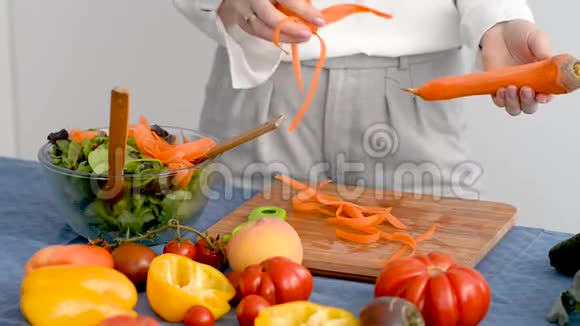 女人的手把胡萝卜皮放在碗里厨房里放着新鲜蔬菜视频的预览图